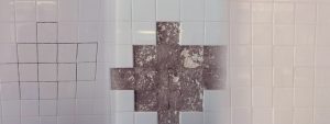 A wall with damaged tiles and cracked grout, illustrating the need for grout replacement in a Colorado home.