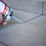 Professional tile sealing process with a technician applying a protective sealant to floor tiles, enhancing durability and appearance