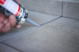 Professional tile sealing process with a technician applying a protective sealant to floor tiles, enhancing durability and appearance